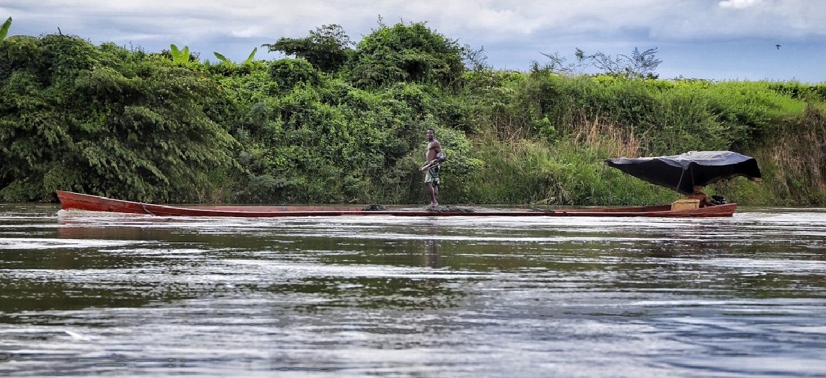 Fotografía de pescador de pie en su embarcación en el río