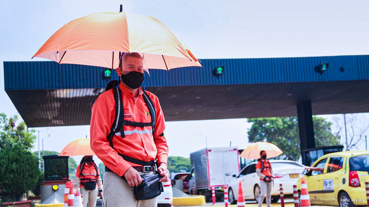 Fotografía de trabajador del INVÍAS en su trabajo de recaudación de peajes bajo la lluvia.