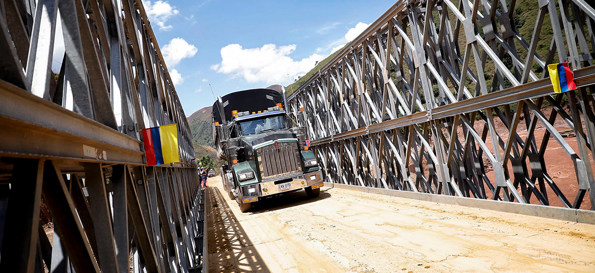 Fotografía del paso de vehículos de carga por el puente metálico provisional en el sector El Tarrita del corredor Ocaña - Cúcuta.