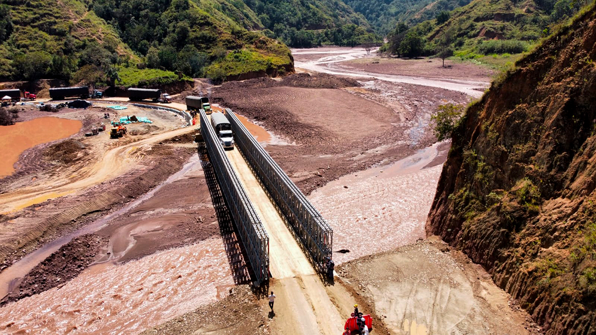 Fotografía del paso de vehículos de carga por el puente metálico provisional en el sector El Tarrita del corredor Ocaña - Cúcuta.