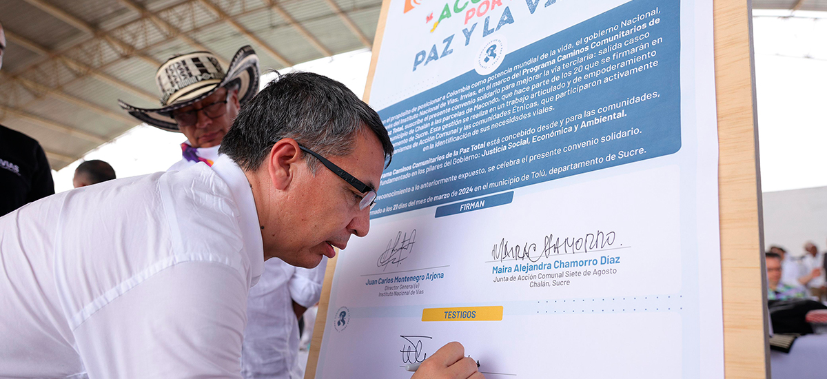 Fotografía de la firma de convenios en Tolú, Sucre entre habitantes de las comunidades beneficiarias y autoridades del gobierno nacional, momento de la firma del ministro de Transporte, William Camargo Triana ante la mirada del presidente de la República, Gustavo Petro Urrego.